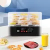 A food dehydrator with multiple trays filled with dried fruit, set on a table with other dried foods and a glass of juice. Produktbild-Vorschau