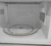 The interior of a white microwave oven with a glass turntable. Produktbild-Vorschau