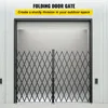 A folding security gate is installed in an open doorway of a building with corrugated metal siding. Anteprima dell’immagine prodotto