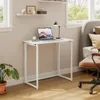 A small white folding desk with a laptop, a cup, and a lamp is set up in a room next to a bed. Produktbild-Vorschau