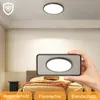 A bedroom scene with a ceiling light and a hand holding a phone showing the light. Voir les images du produit