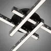 A close-up, angled view of a modern, black LED ceiling light fixture with multiple intersecting arms, each featuring a strip of white light and a perforated, sparkling surface. Produktbild-Vorschau