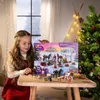 A young girl is holding an advent calendar with a horse theme next to a Christmas tree. Produktbild-Vorschau