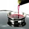 Red liquid being poured from a bottle into a small metal dish. Produktbild-Vorschau