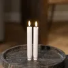 Two white LED candles with lit flames stand on a dark, textured tray. Produktbild-Vorschau