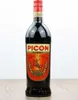 A bottle of Amer Picon aperitif sits on a wooden surface against a white background. Anteprima dell’immagine prodotto