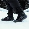 A person wearing black pants and black winter boots with pink accents walking in the snow. Podgląd zdjęcia produktu