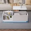 A modern white coffee table with a lift-top and storage is placed in a living room setting, in front of a sofa. Náhľad obrázku produktu