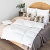 A neatly made bed with a white comforter and several pillows. Produktbild-Vorschau