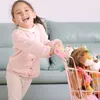 A young girl is happily pushing a toy shopping cart filled with stuffed animals. Anteprima dell’immagine prodotto