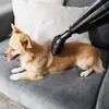 A dog is lying on a couch while a vacuum cleaner attachment is being used on its fur. Podgląd zdjęcia produktu