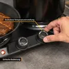A close-up of a person's hand adjusting the temperature knob on a black electric double hot plate, with a steak cooking in a pan on one of the burners. Produktbild-Vorschau