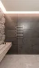 A modern bathroom with a stone feature wall, wood shelf, and a heated towel rack. Podgląd zdjęcia produktu