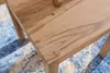 A close-up view of a wooden table with a patterned rug underneath. Anteprima dell’immagine prodotto