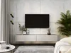 A modern living room with a TV mounted on a concrete wall above a floating media console. A floor lamp and a plant are also visible. Voir les images du produit