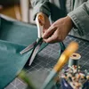 A person is using pinking shears to cut teal fabric on a cutting mat. Náhľad obrázku produktu