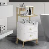 A rolling cart with two drawers and two shelves, decorated with a marble pattern, is shown in a bathroom setting next to a bathtub. Produktbild-Vorschau