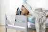 A young boy is lying in bed, covered by a blanket, and holding a walkie-talkie. Produktbild-Vorschau