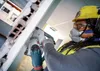 A person wearing safety gear is using a power tool to cut into a wall. Voir les images du produit
