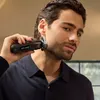 A man is holding a black electric shaver to his ear. Náhled obrázku produktu