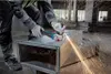 A person is using an angle grinder to cut a metal duct in a workshop. Náhľad obrázku produktu