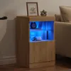 A wooden sideboard with blue LED lighting is shown in a living room setting next to a sofa. Produktbild-Vorschau