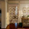 A wooden beaded curtain hangs in a doorway, separating two rooms. The room to the right has a wooden cabinet with decorative carvings, framed pictures on the wall, and a potted plant. Podgląd zdjęcia produktu