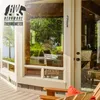 An outdoor thermometer attached to a patio door frame overlooking a lush green garden and water. Anteprima dell’immagine prodotto