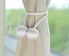 A close-up of a pair of decorative curtain tie-backs with silver balls, holding back a sheer beige curtain. Náhľad obrázku produktu