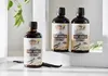 Three bottles of vanilla extract are displayed on a shelf with vanilla beans. Produktbild-Vorschau