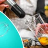 A person is using a hand blender to whisk eggs in a glass beaker. Produktbild-Vorschau