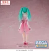 A figurine of Hatsune Miku standing on a clear display base against a pink background. Produktbild-Vorschau