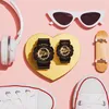 A flat lay of accessories including watches, headphones, sunglasses, a skateboard, and sneakers on a pink background. Anteprima dell’immagine prodotto