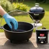A person wearing blue gloves is cleaning a cast iron pot with a sponge, with a black grill in the background and a jar of cleaning paste on the table. Produktbild-Vorschau