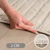 A hand pressing down on a thick rug, with a close-up inset showing the rug's thickness. Voir les images du produit