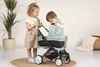Two children playing with a doll stroller indoors. Produktbild-Vorschau