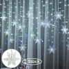 A curtain of snowflake-shaped lights hanging against a sheer white curtain. Náhled obrázku produktu