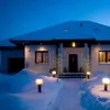 A house decorated with lights in the snow at night. Podgląd zdjęcia produktu