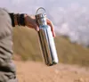 A person holding a stainless steel water bottle outdoors. Podgląd zdjęcia produktu