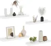 Four white shelves are displayed against a white background, each holding various decorative items. Produktbild-Vorschau