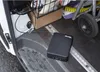 A black Master Lock portable safe is secured with a cable inside a van. Podgląd zdjęcia produktu
