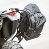 A close-up view of a black adventure pack attached to a motorcycle's luggage rack. Produktbild-Vorschau