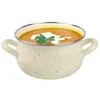 A pot of soup with a dollop of cream and a sprig of parsley on top, set against a white background. Produktbild-Vorschau