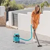 A woman is vacuuming an outdoor patio with a turquoise wet and dry vacuum cleaner. Produktbild-Vorschau