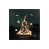 A 3D mechanical cello model is displayed on a book, with scattered sheet music around it, and a miniature piano in the background. Voir les images du produit
