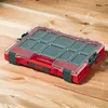 A red and clear plastic tool organizer with multiple compartments sits on a wooden surface. Náhled obrázku produktu