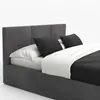 A close-up view of a bed with a graphite upholstered frame, white sheets, and black decorative pillows. Produktbild-Vorschau