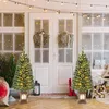 Two decorated Christmas trees are placed on a porch in front of a double door, with Christmas lights strung overhead. Podgląd zdjęcia produktu