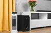 A white ceramic heater and a black subwoofer are placed next to a white media console with a vase of flowers on top. Voir les images du produit