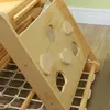 A close-up view of a wooden Montessori climbing structure for children, showing climbing holds and a net. Produktbild-Vorschau